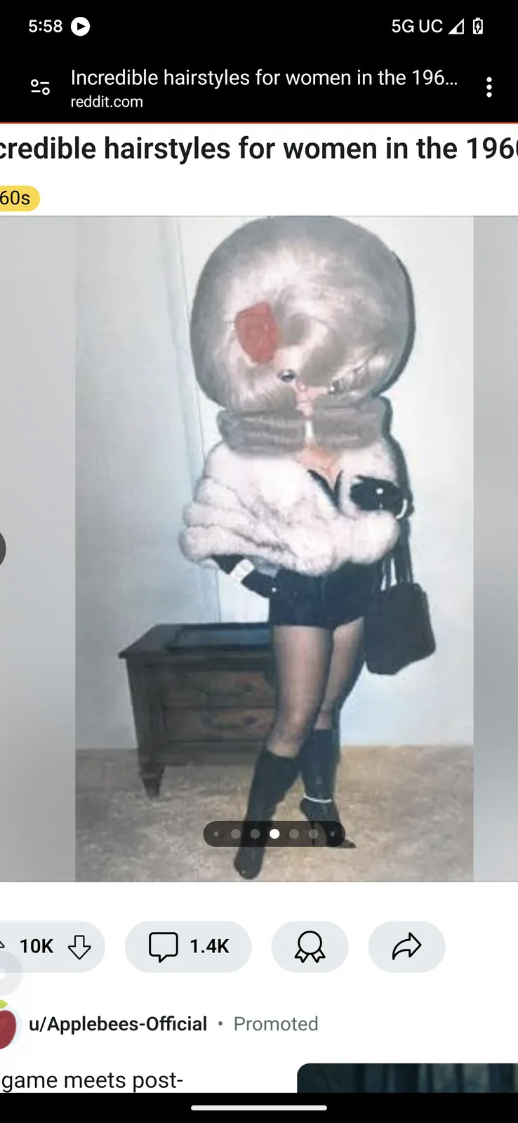 A grainy, vintage photo shows a woman in 1960s attire with a massive, round, fluffy hairstyle that obscures her face…