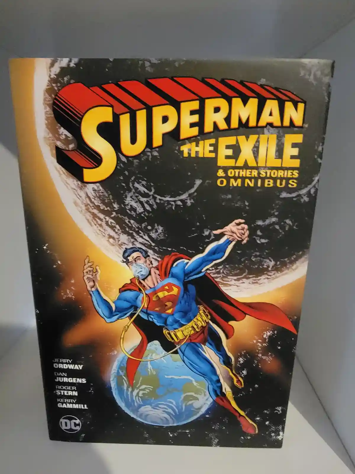 The cover of a DC Comics 'Superman: The Exile & Other Stories Omnibus' book shows Superman flying in space with Earth below…