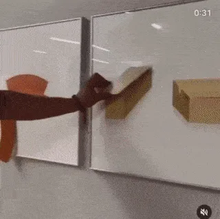 A person uses orange adhesive strips to create a 3D geometric shape on a whiteboard, then replaces the strips with black…