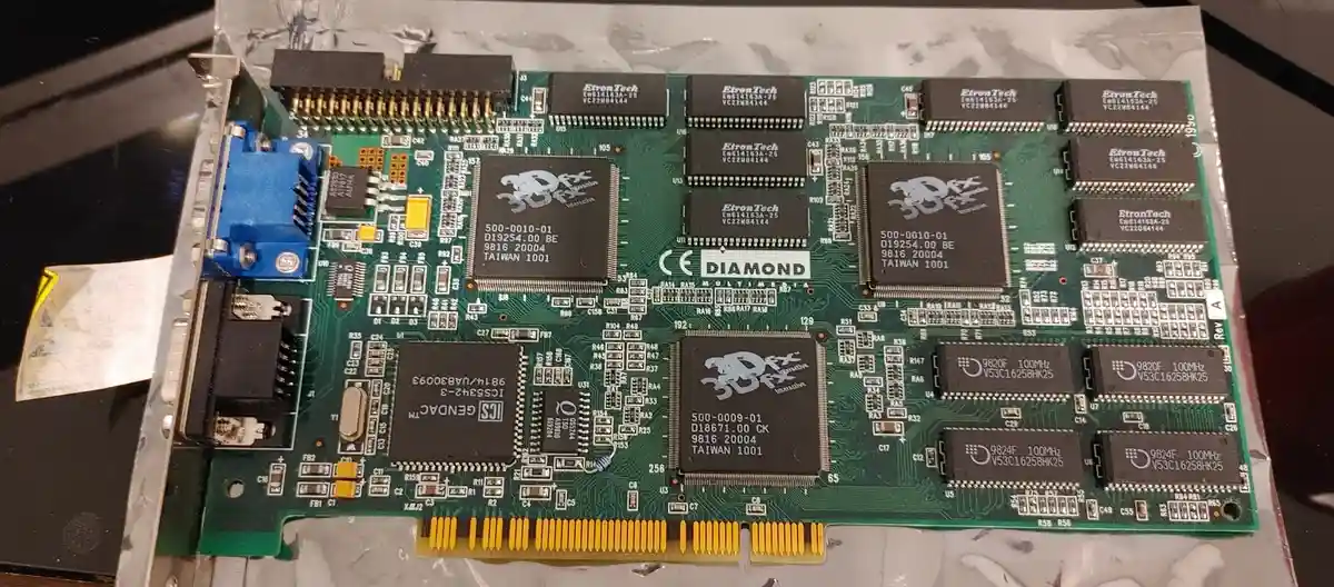 A close-up photo of a green Diamond Multimedia 3dfx Voodoo graphics card from 1999, showing multiple black chips with '3dfx…