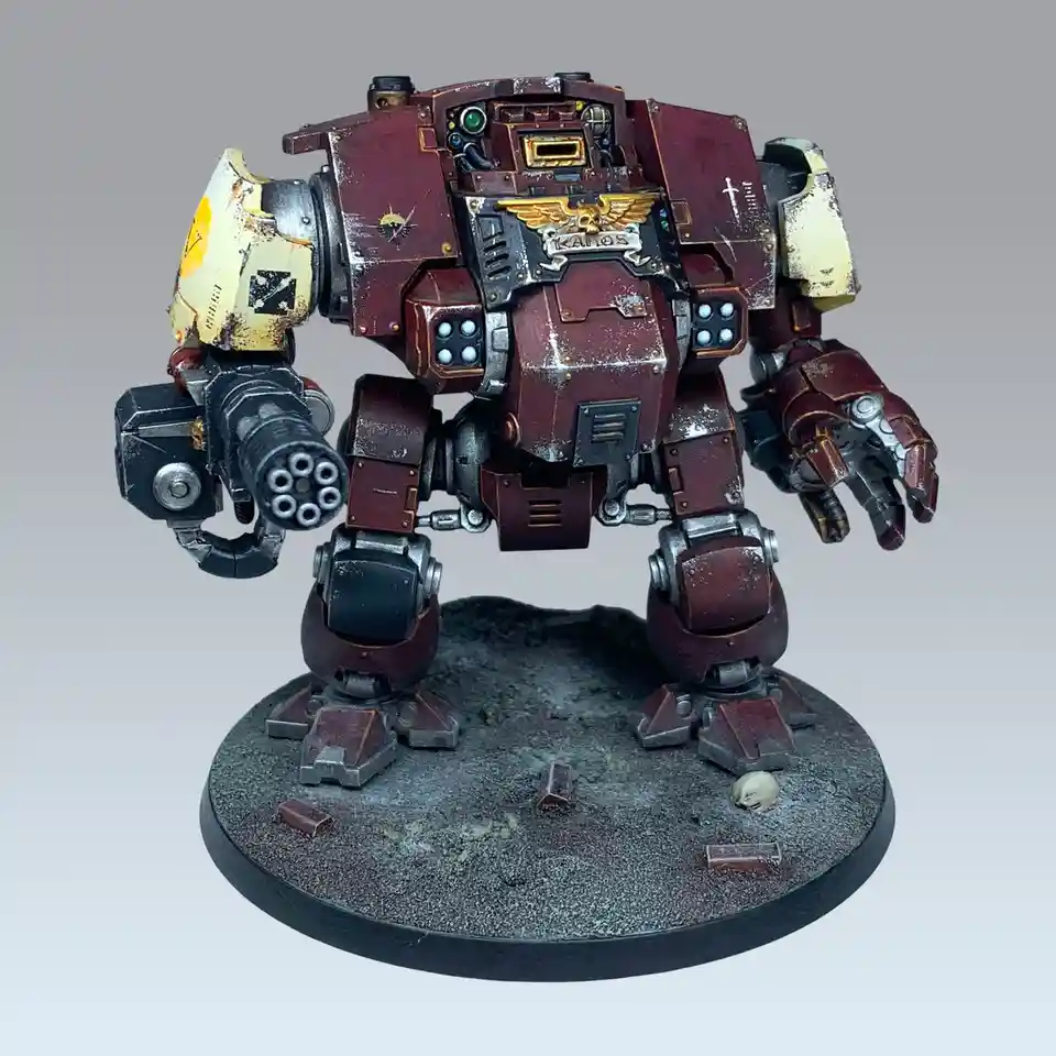 A heavily weathered, maroon and cream-colored Warhammer 40k Land Raider-style mech stands on a circular base with rubble and…
