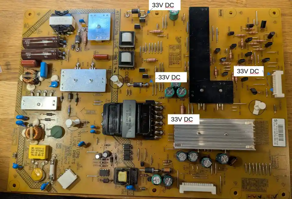 A yellow circuit board with various electronic components like capacitors, resistors, and transformers is shown on a wooden…