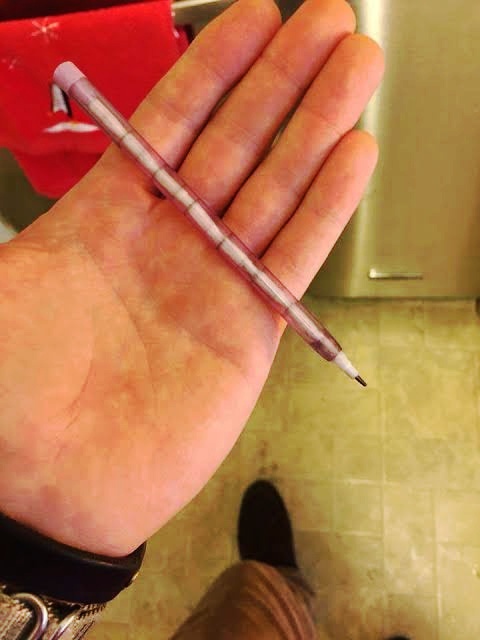 A close-up photo shows a hand holding a thin, translucent purple pen with a fine black tip. The pen is positioned…
