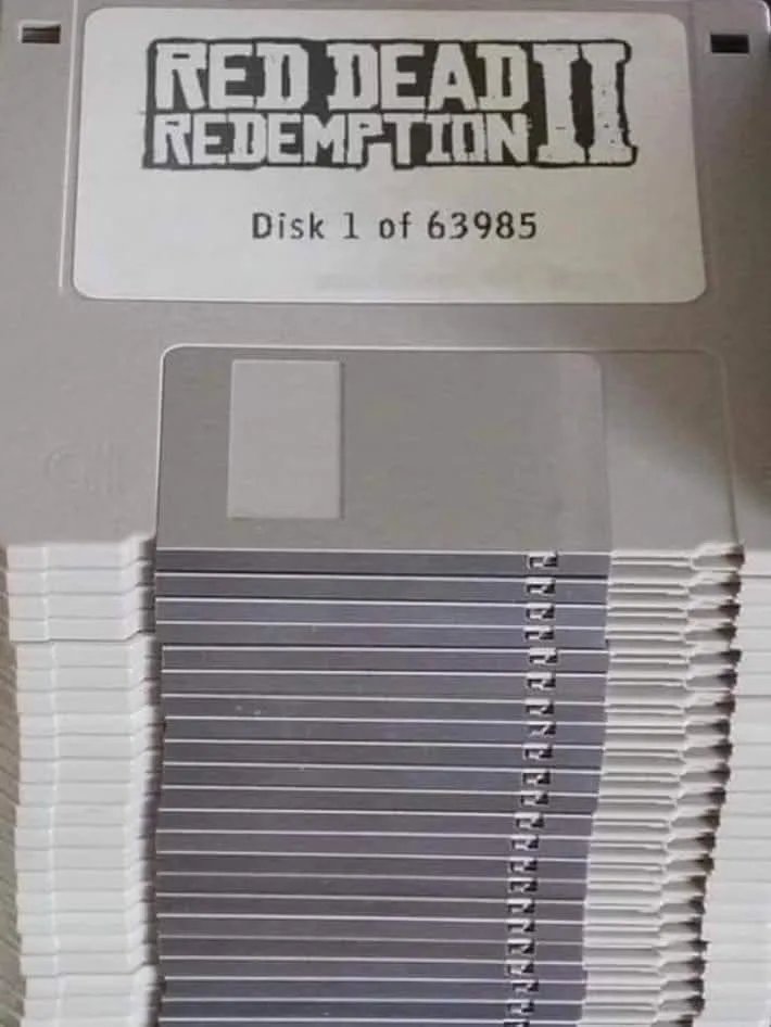 A towering stack of floppy disks, with the top one labeled 'Red Dead Redemption II' and 'Disk 1 of 63985', humorously…