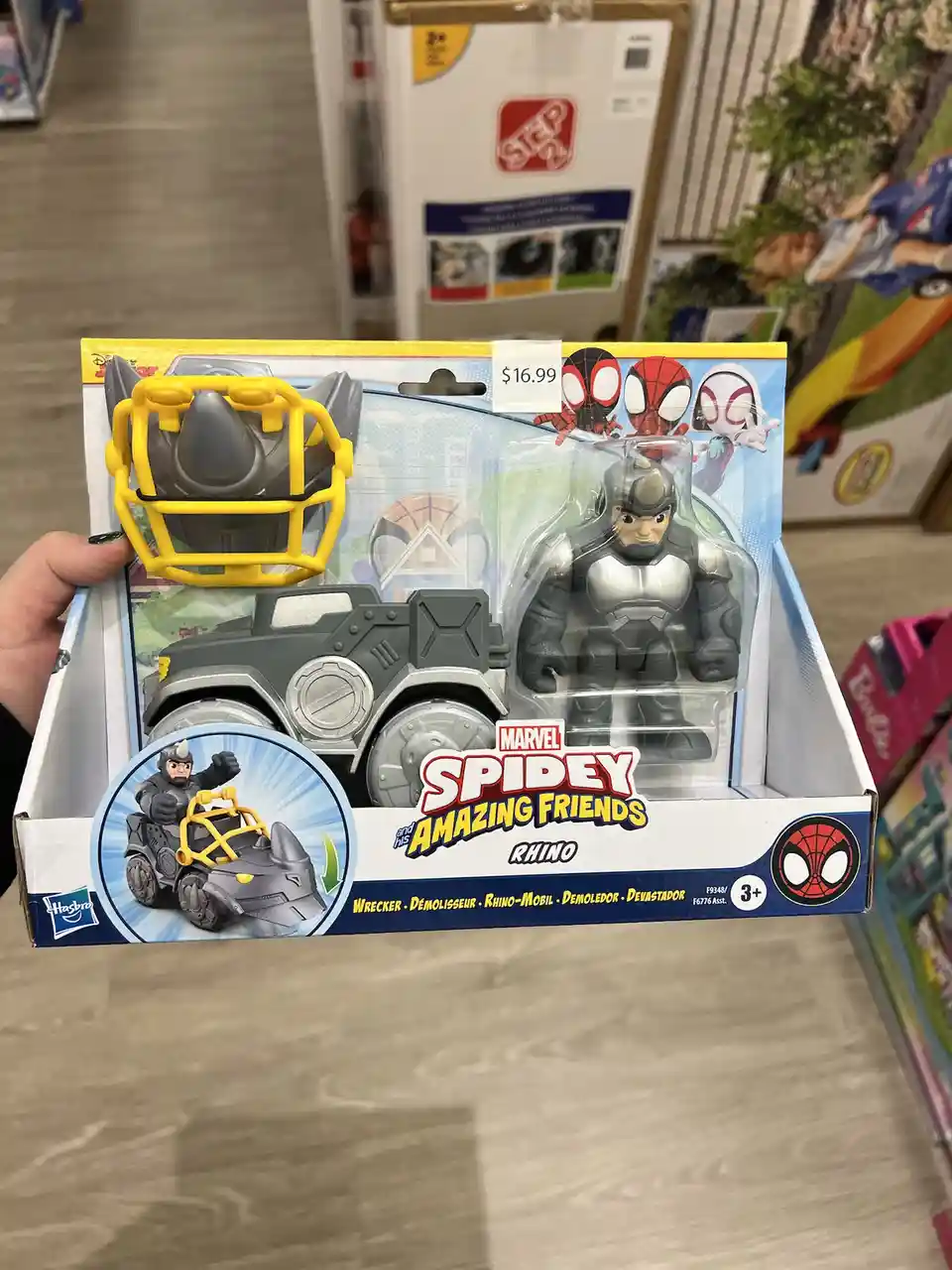A hand holds a Hasbro toy package for 'Marvel Spidey and his Amazing Friends' featuring the character Rhino, which includes…