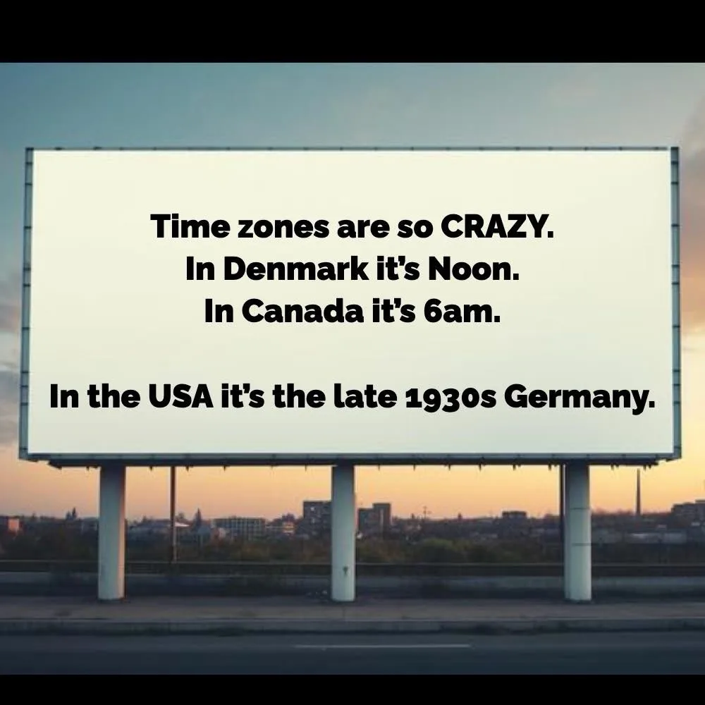 A large white billboard stands on a highway at dusk, displaying black text that reads 'Time zones are so CRAZY. In Denmark…
