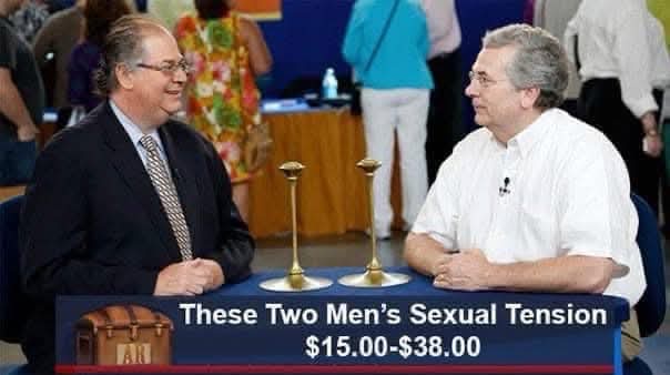 Two men in suits sit across a table with two golden candlesticks between them. A blue banner at the bottom reads 'These Two…