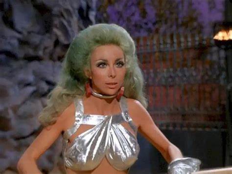 A woman with voluminous green hair and a shiny silver top stands with one hand on her hip. The overlaid text reads 'i'm not…