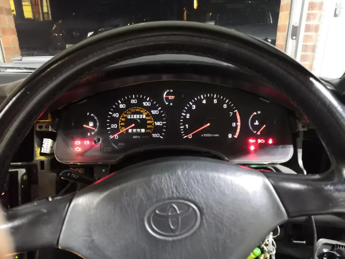 A close-up photo of a Toyota car's dashboard at night, showing the odometer reading 118927 miles, with multiple warning…
