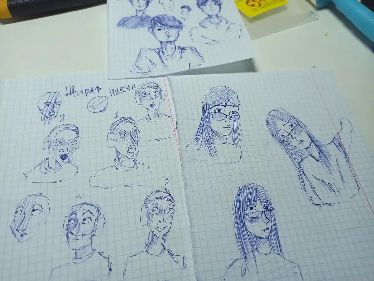 На клетчатой бумаге лежат несколько набросков аниме-стиля лиц с разными выражениями: удивление, улыбка, серьезное выражение…