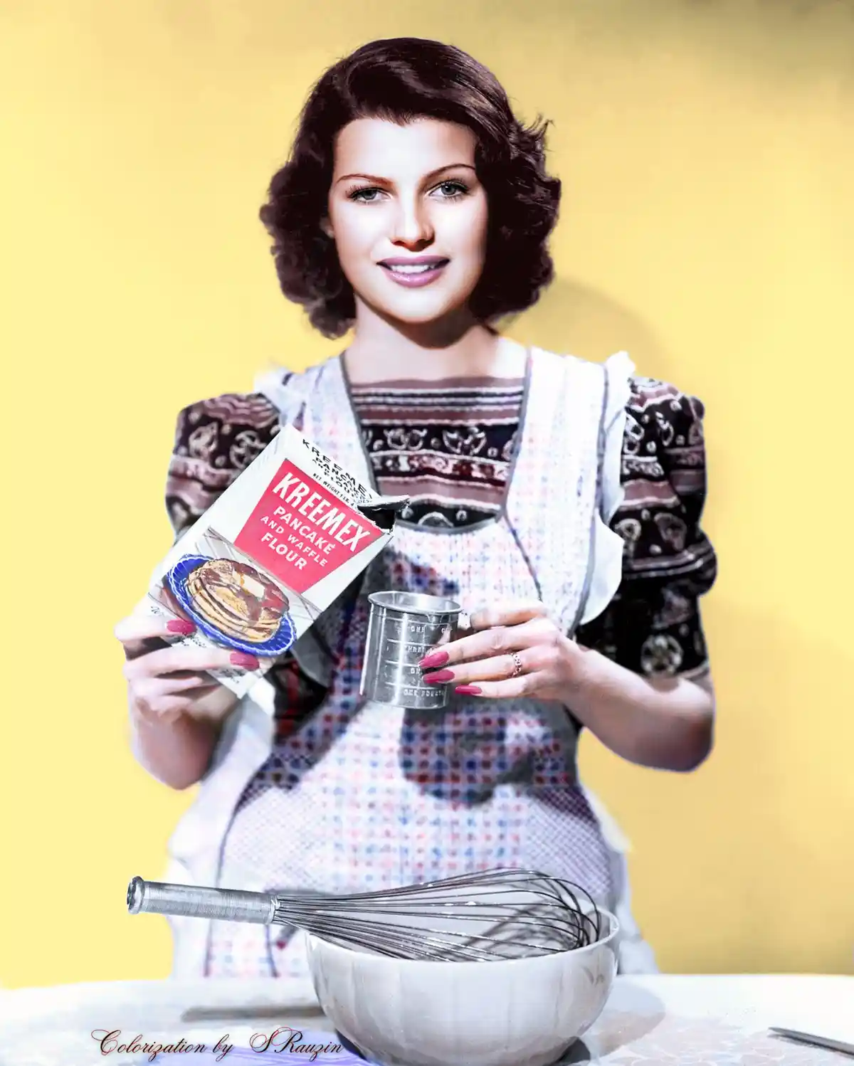 A vintage colorized photo shows a smiling woman in an apron holding a box of Kreemex Pancake and Waffle Flour and a…