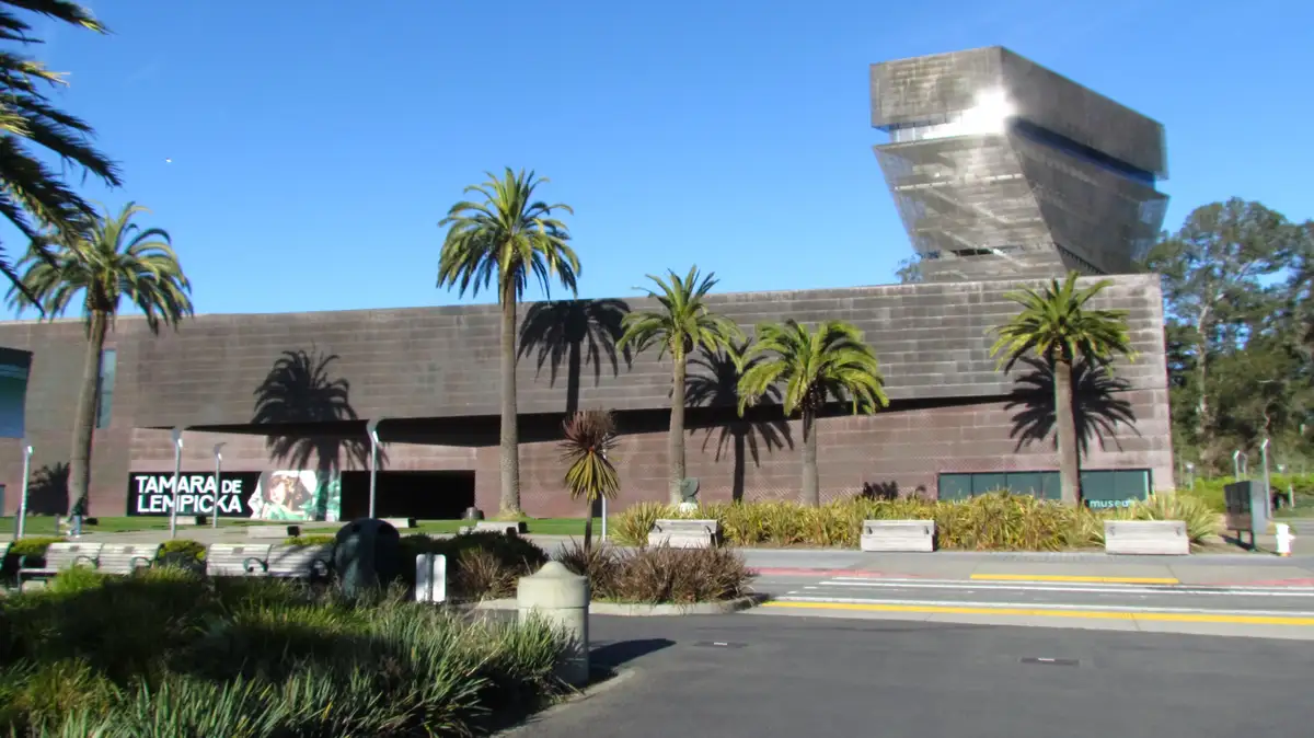 An exterior photo of the de Young Museum in San Francisco, featuring its distinctive modern architecture with a prominent…