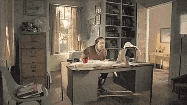 A split-screen image shows a man at a desk in a home office. In the top row, he is initially focused on his laptop, then…