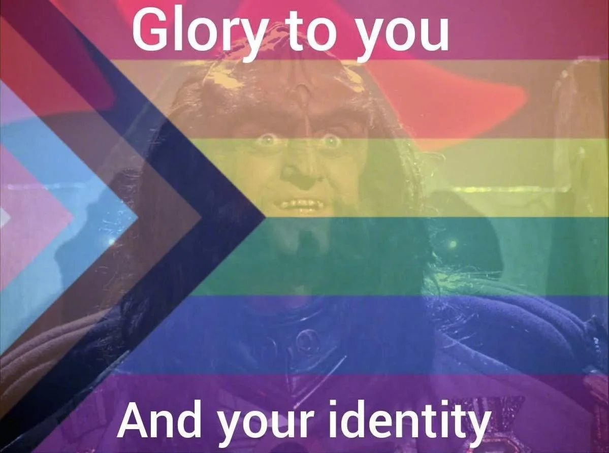 A close-up image of a demonic-looking character with wide eyes and a menacing expression, overlaid with a rainbow flag…