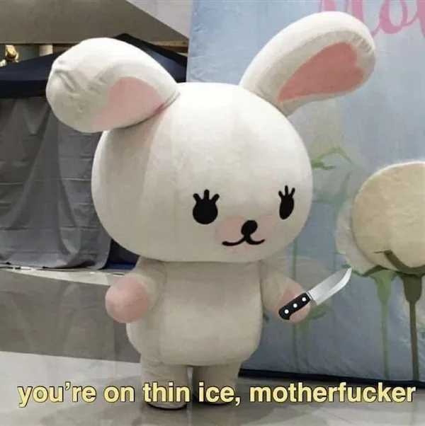 A person in a large, white, plush rabbit mascot costume stands indoors holding a small kitchen knife in their right hand…