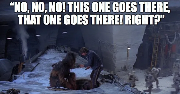 In a snowy, industrial setting from Star Wars, Han Solo leans over a hole while Chewbacca sits beside him, both gesturing…