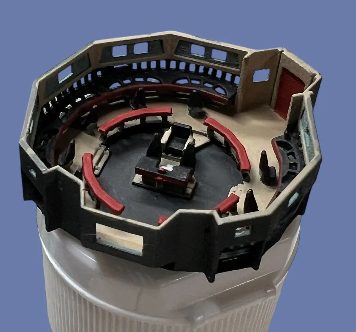 a miniature model of the star wars senate chamber, featuring a central chair surrounded by curved red seats and a black…