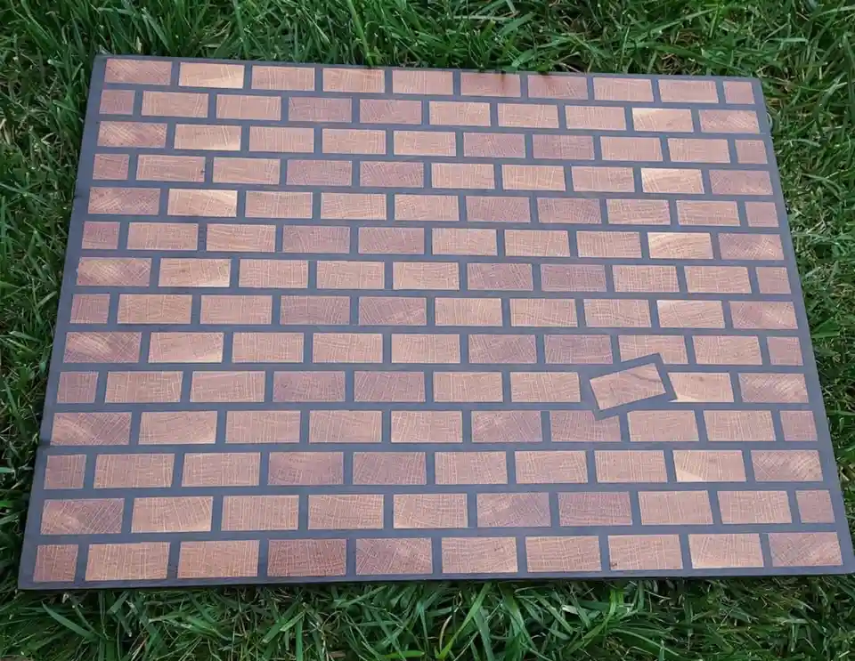 A wooden board with a brick pattern laid on grass, where one brick is missing and slightly askew, with the text 'i'm not…