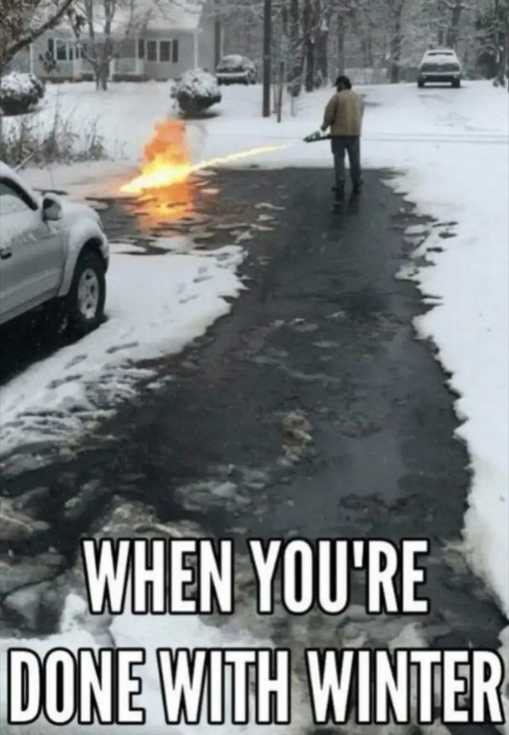 A person stands in a snowy residential street, using a chainsaw to cut through snow and ice, causing a large flame to erupt…