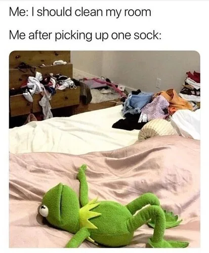 A messy bedroom with clothes strewn across a bed and dresser, featuring a green Kermit the Frog plush toy lying on the bed…