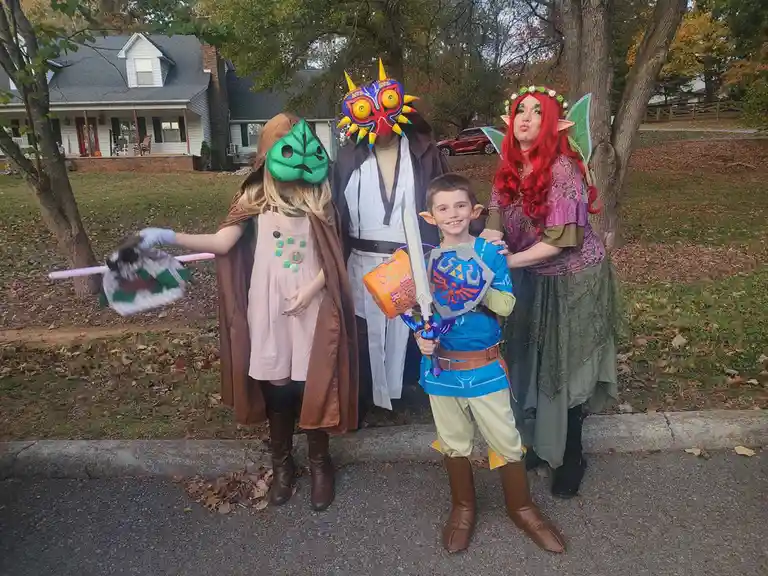 Four people dressed as characters from The Legend of Zelda video game series pose outdoors for a photo. From left to right…