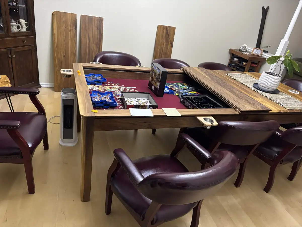 A large wooden game table with a red felt surface is shown in a room, partially open to reveal storage compartments. Puzzle…