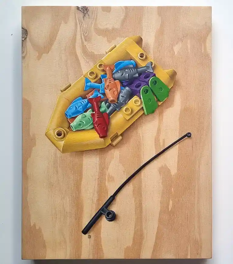 A painting depicts a yellow LEGO boat filled with colorful LEGO fish on a wooden surface, with a black LEGO fishing rod…