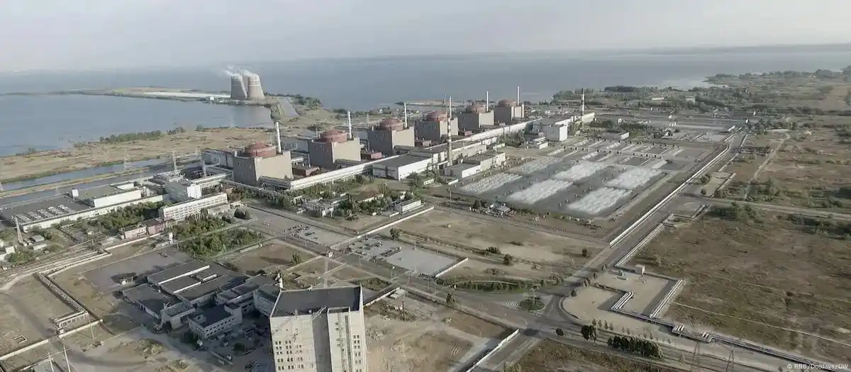 an aerial photograph shows a large industrial complex with multiple cooling towers and reactor buildings situated next to a…