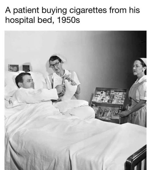 A black-and-white photo from the 1950s shows a man in a hospital bed reaching for a cigarette pack held by a nurse. Another…