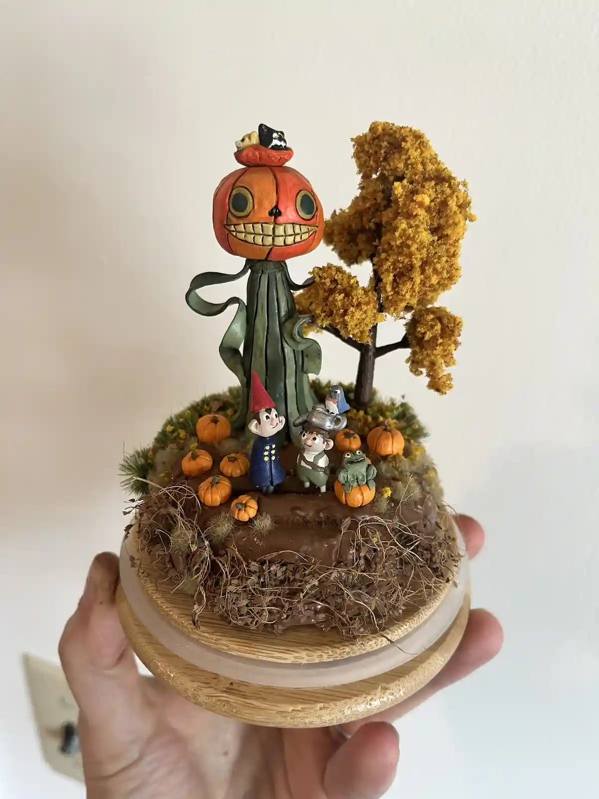 A hand holds a small, detailed diorama featuring Jack Skellington from The Nightmare Before Christmas, standing tall with a…