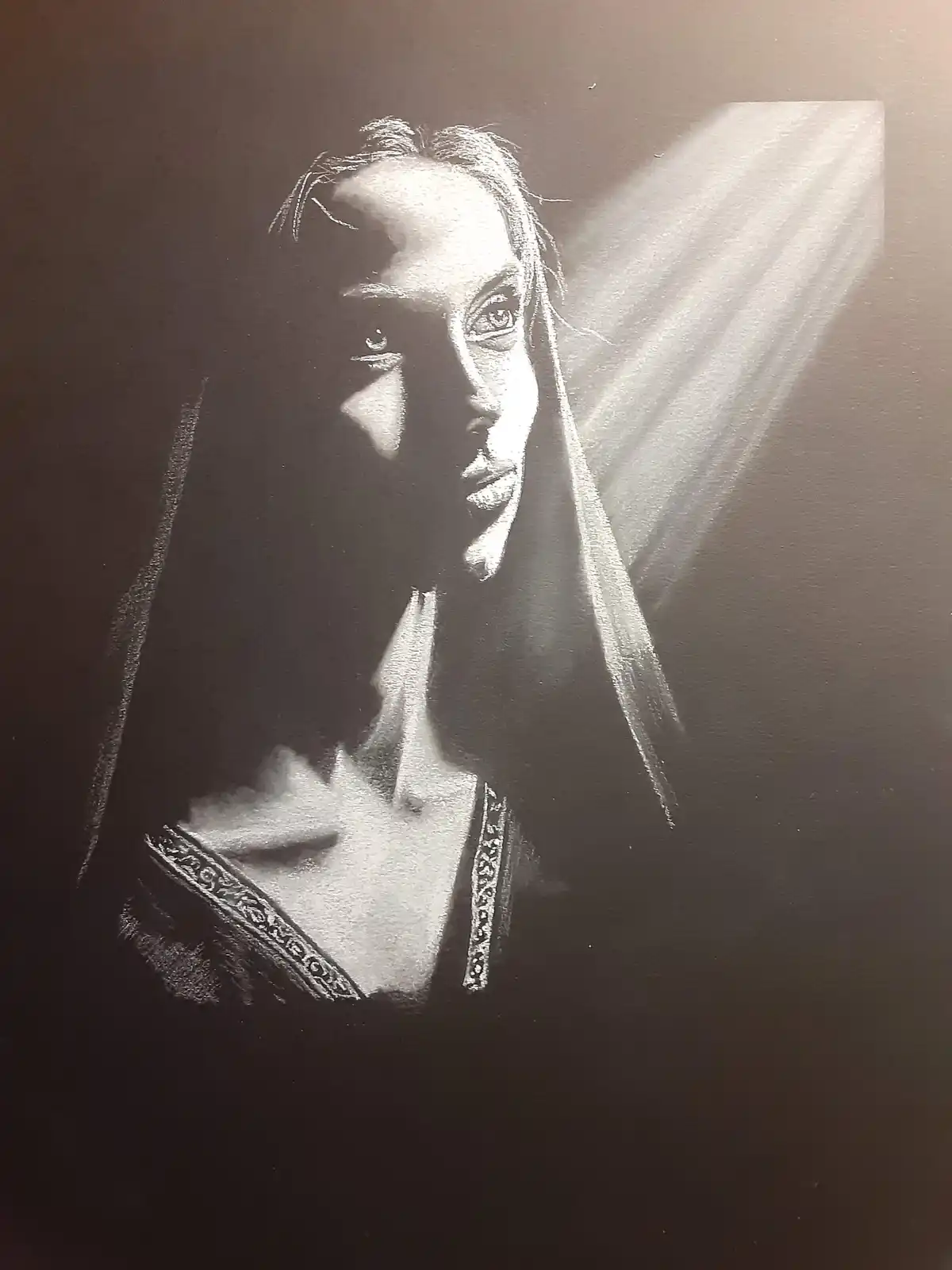 A black and white image of Angelina Jolie in a dramatic, high-contrast lighting style, with a beam of light illuminating her…