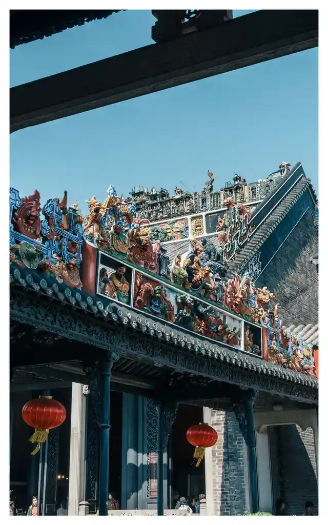 this is a photo of a traditional chinese temple roof with intricate ceramic figurines and red lanterns hanging below. the…