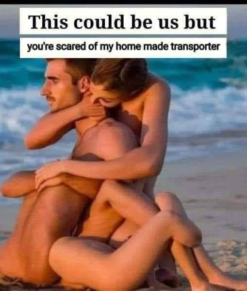 A man and woman are sitting closely together on a beach, with the woman embracing the man from behind. The image has text…