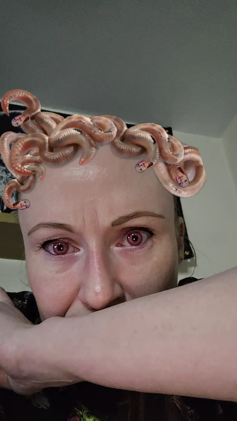 A close-up selfie of a woman with wide, intense eyes and her arm across her face, digitally edited to have multiple…