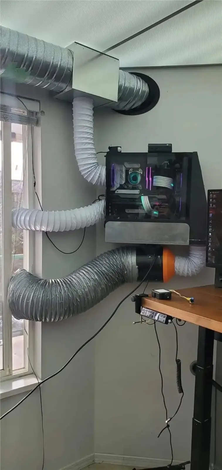 A computer case is mounted on a wall with multiple large flexible ducts connected to it, leading to a vent in the ceiling…