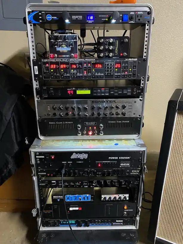 A tall, stacked rack of professional audio equipment, including amplifiers, effects processors, and power conditioners, with…