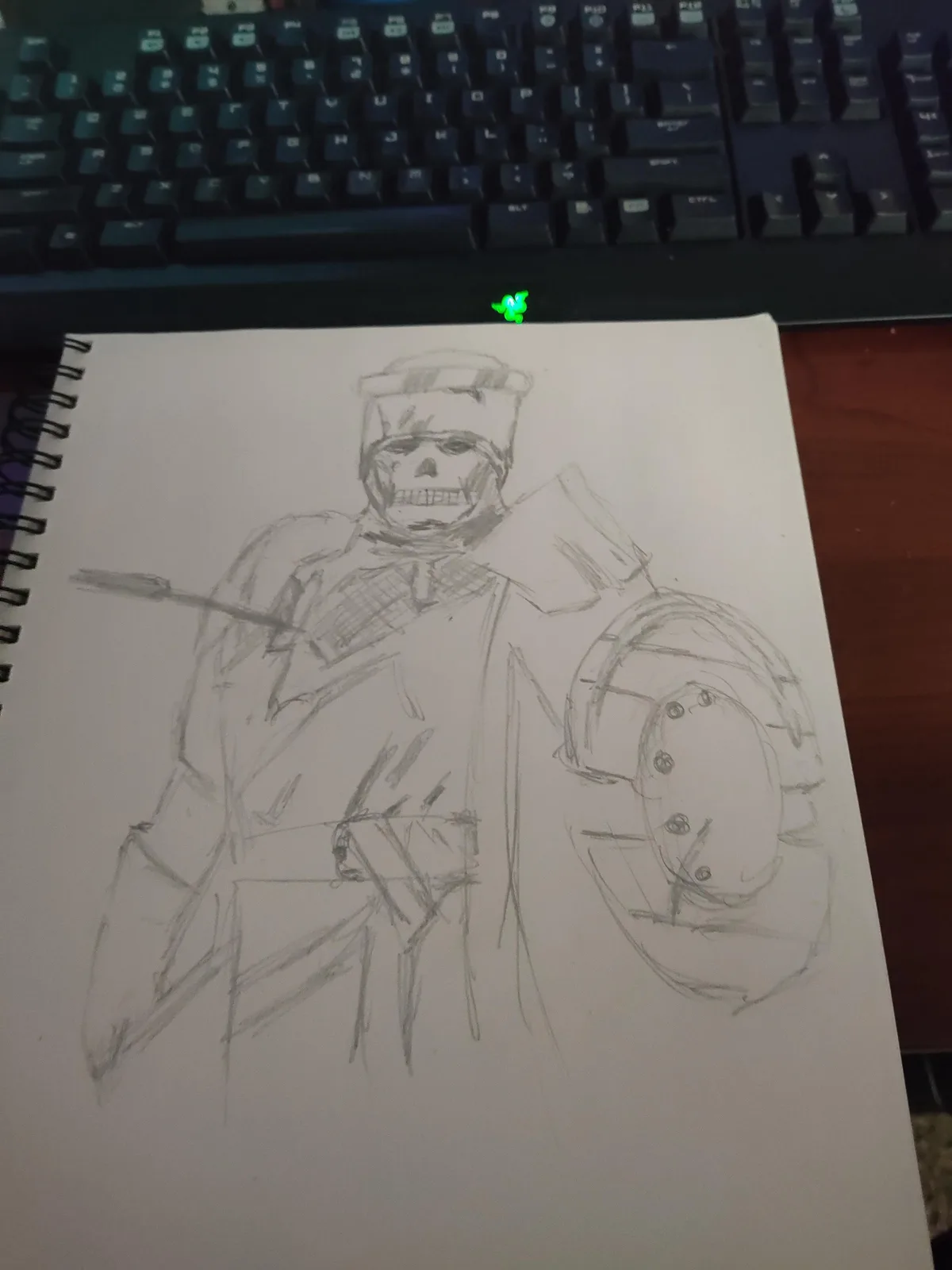 A hand-drawn pencil sketch on a spiral-bound notebook page depicts a skeletal figure wearing a military-style uniform and…
