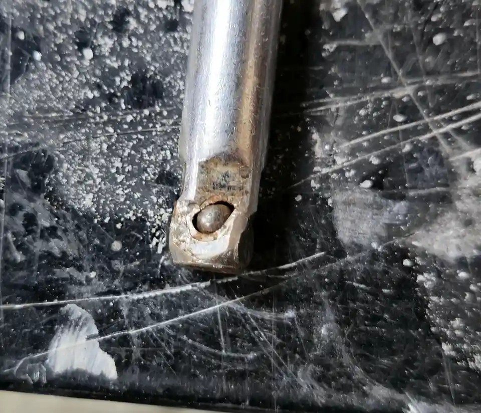 A close-up photo shows a rusty metal rod with a bolted joint resting on a scratched, dirty black surface. The overlaid text…