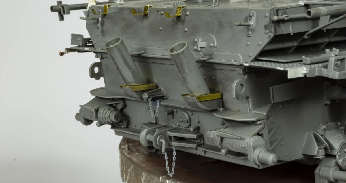 A close-up photo of a detailed grey scale model of a military tank's side, showing rivets, hatches, and mechanical parts…