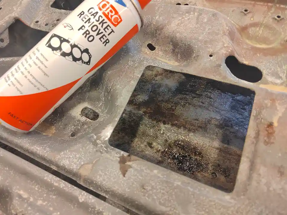 A can of CRC Gasket Remover Pro sits on a dirty, rusty, and corroded metal engine block surface, implying the product is…