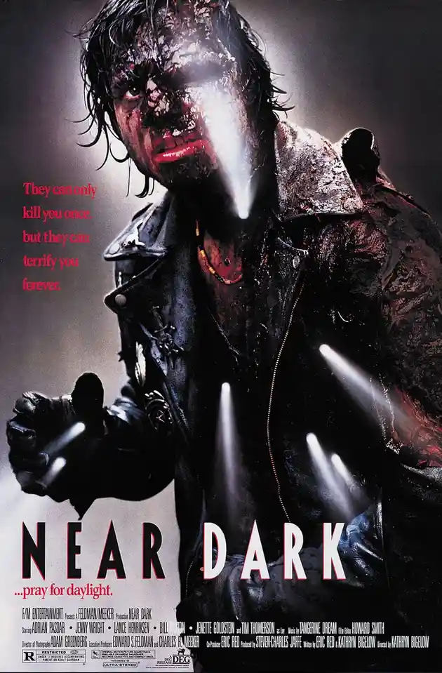 A movie poster for 'Near Dark' shows a bloodied, menacing man in a leather jacket with a glowing white beam shooting from…