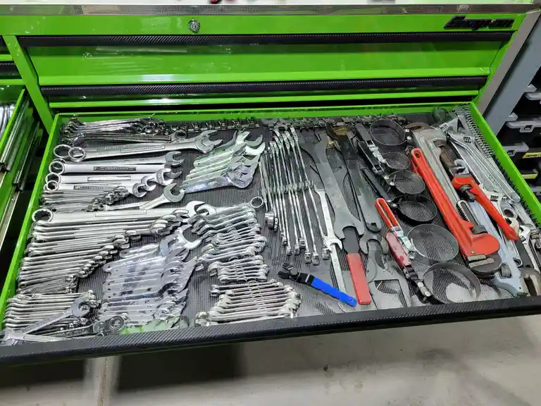 An open, bright green Snap-on tool chest drawer is filled with an extensive, meticulously organized collection of wrenches…