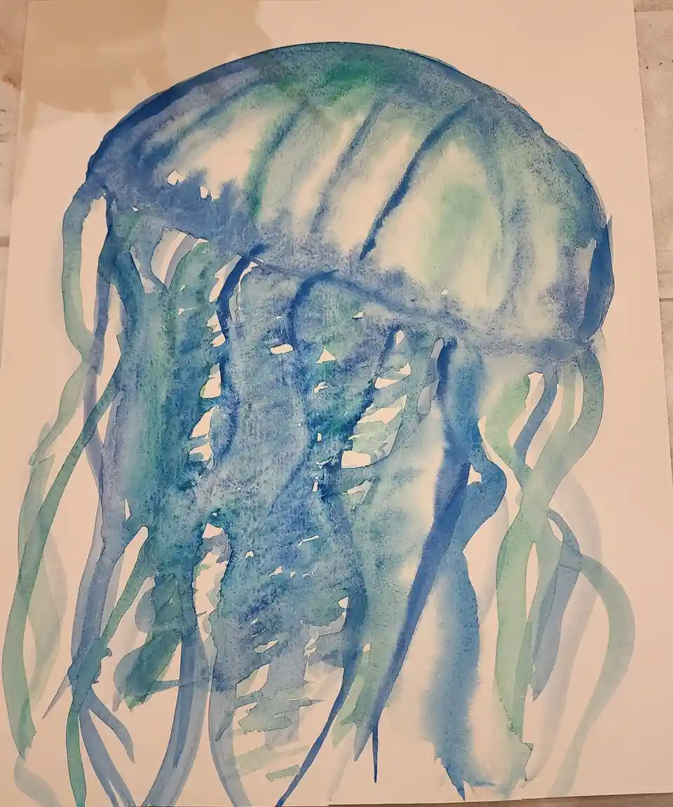 A watercolor painting of a jellyfish rendered in shades of blue and green on white paper, with visible brushstrokes and…
