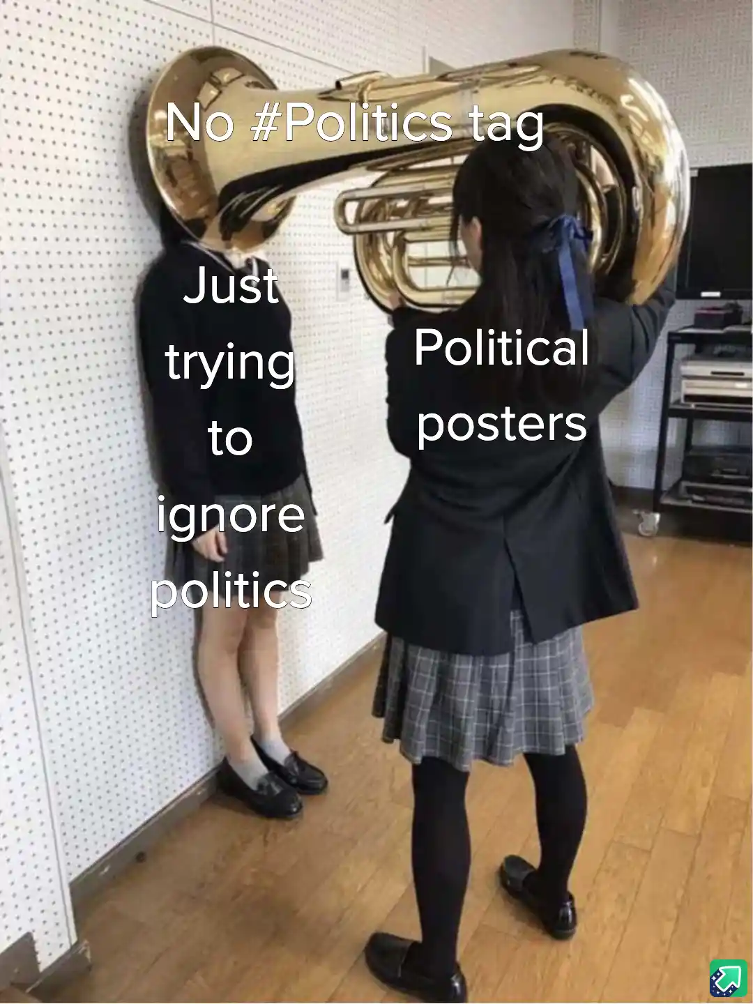 Two schoolgirls in uniforms stand in a room with a large brass tuba. One girl leans against a wall, while the other holds…