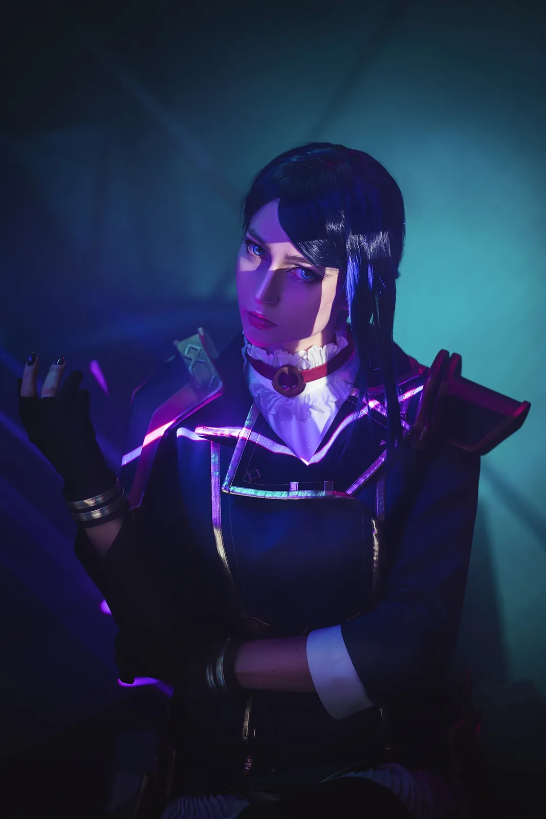 A person in a detailed cosplay of a character with dark hair, glowing purple and blue lighting, and a black outfit with…