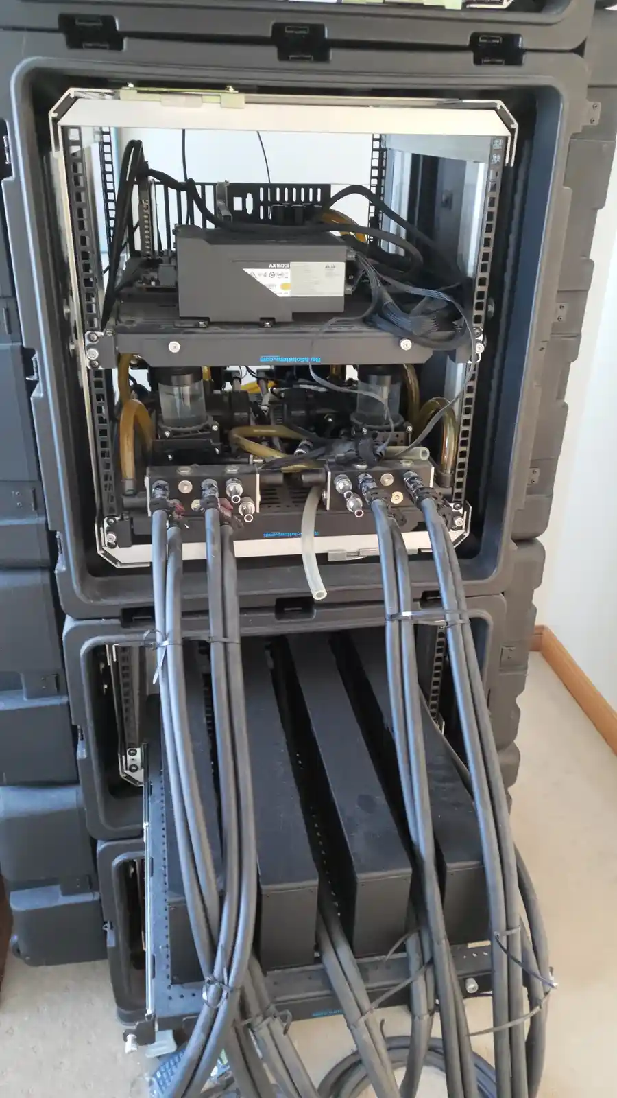 The image shows a large, open, rugged black case revealing a complex, densely packed piece of industrial or scientific…
