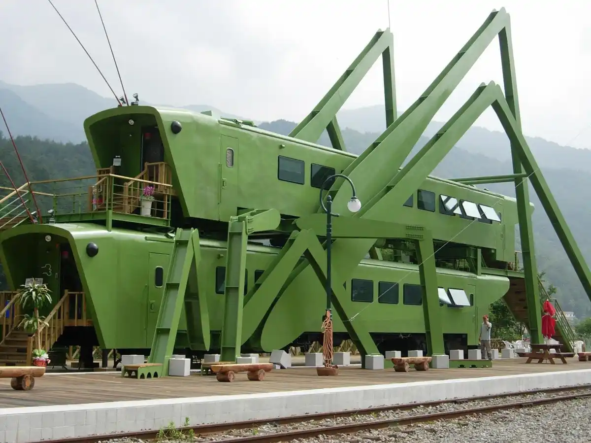 a large, bright green train car has been modified to resemble a giant cricket, with oversized legs and antennae, parked at a…