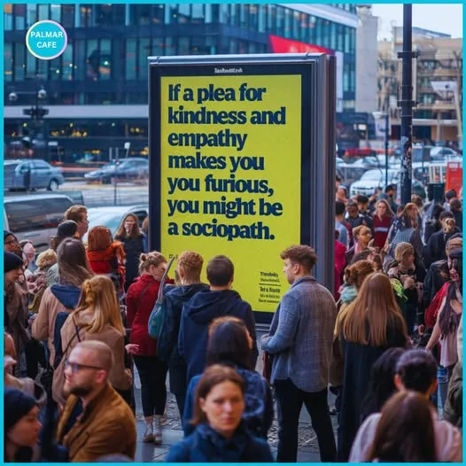 A large yellow billboard in a busy city street displays the text 'If a plea for kindness and empathy makes you furious, you…