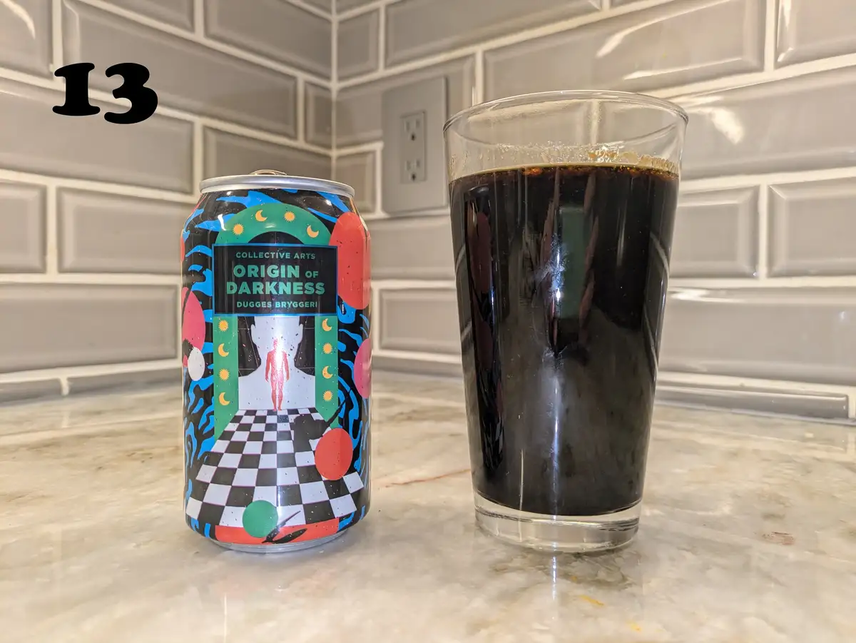 A beer can labeled 'Origin of Darkness' by Dugges Bryggeri sits next to a glass filled with dark beer on a kitchen counter…