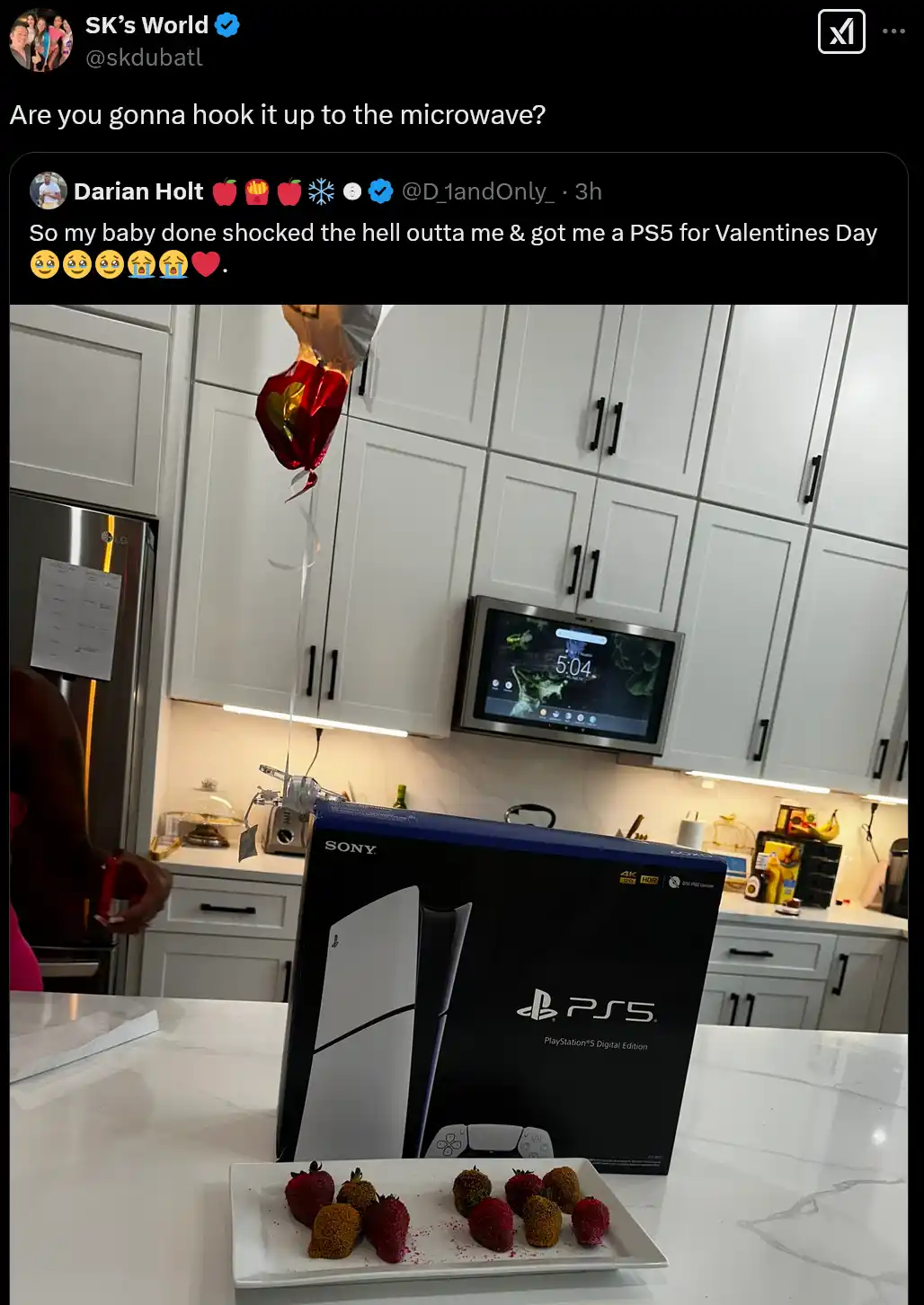 A photo shows a PlayStation 5 Digital Edition box on a kitchen counter, with a plate of chocolate-covered strawberries in…